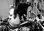 Helmeted motorcyclist mounts up in the street.